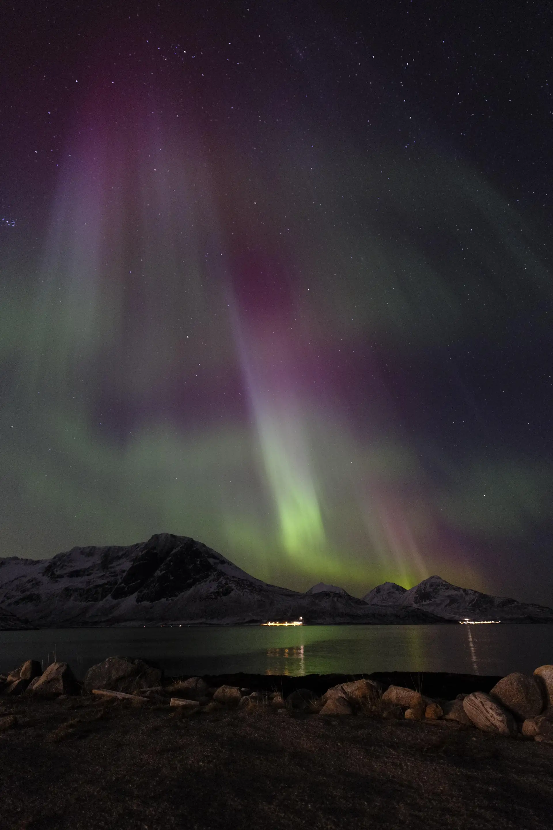 Grønt nordlys over en mørk fjellrygg