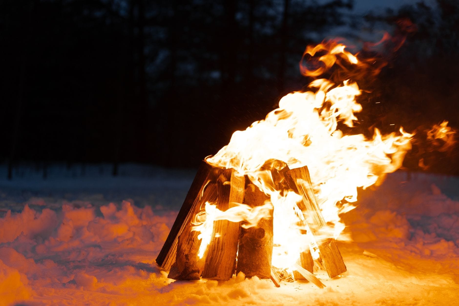 Et bål som brenner i dyp snø i skumringen